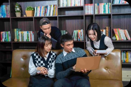 CMoney 同事在書牆前的沙發上圍著筆電一起討論